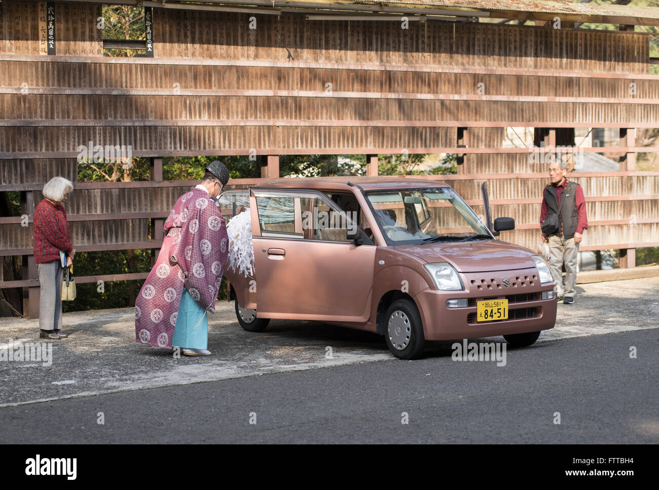 Prêtre shintoïste bénit une nouvelle voiture comme les propriétaires à regarder Kibitsu Shrine, préfecture d'Okayama, Japon. Banque D'Images