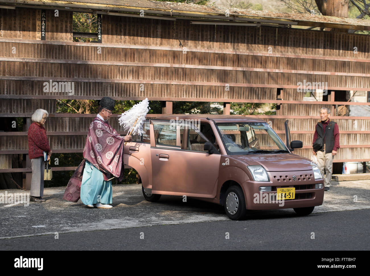 Prêtre shintoïste bénit une nouvelle voiture comme les propriétaires à regarder Kibitsu Shrine, préfecture d'Okayama, Japon. Banque D'Images