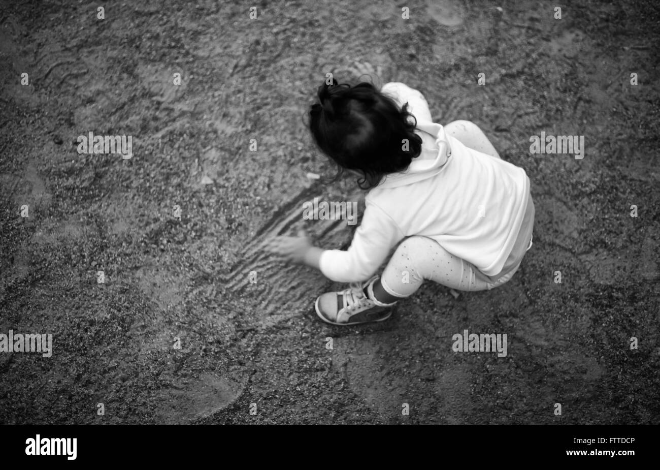 Petite fille brune retour high view jouant sur le sable du parc Banque D'Images