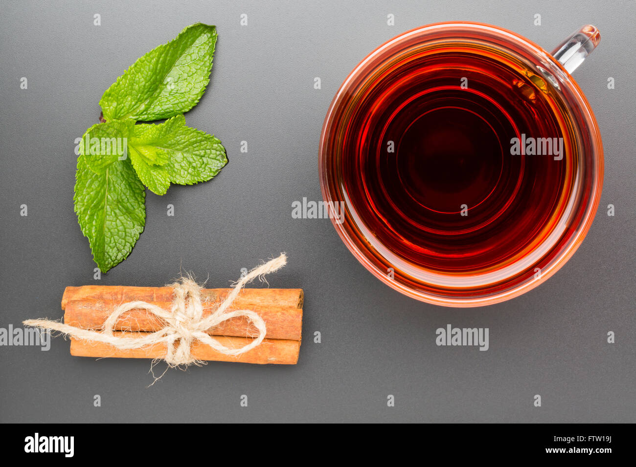 Tasse en verre de thé à la menthe et le bâton de cannelle sur le fond noir Banque D'Images