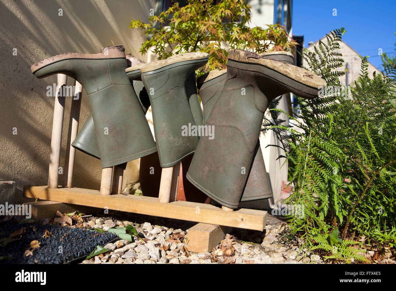 Quatre paires de bottes wellington ou la gomme stockés sur un support à bottes à l'extérieur d'une porte avant pour les garder au sec et propre. Banque D'Images