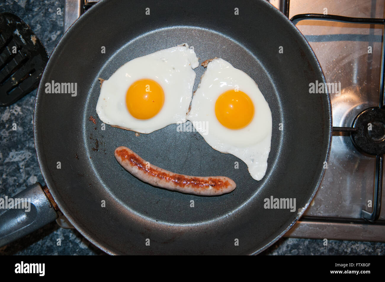 Deux œufs au plat et d'une saucisse faire un visage dans la casserole Banque D'Images