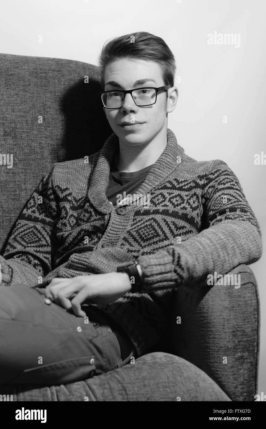 Jeune homme portant des lunettes, se détendre dans une chaise à ailes Banque D'Images