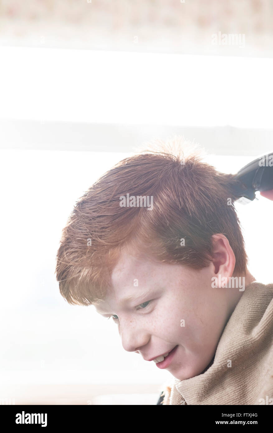 Un garçon ayant ses cheveux coupés avec clippers et des ciseaux. Banque D'Images