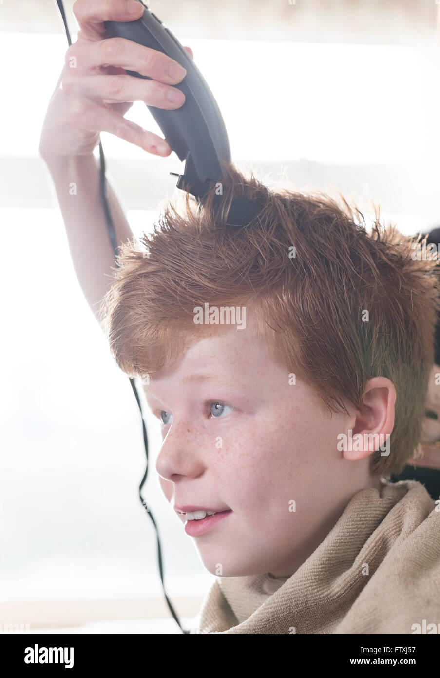 Un garçon ayant ses cheveux coupés avec clippers et des ciseaux. Banque D'Images