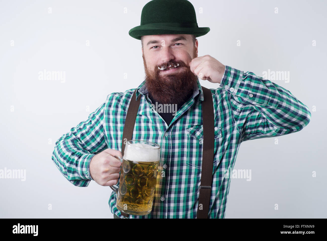 Homme tenant un verre de bière et faisant tournoyer sa moustache Banque D'Images