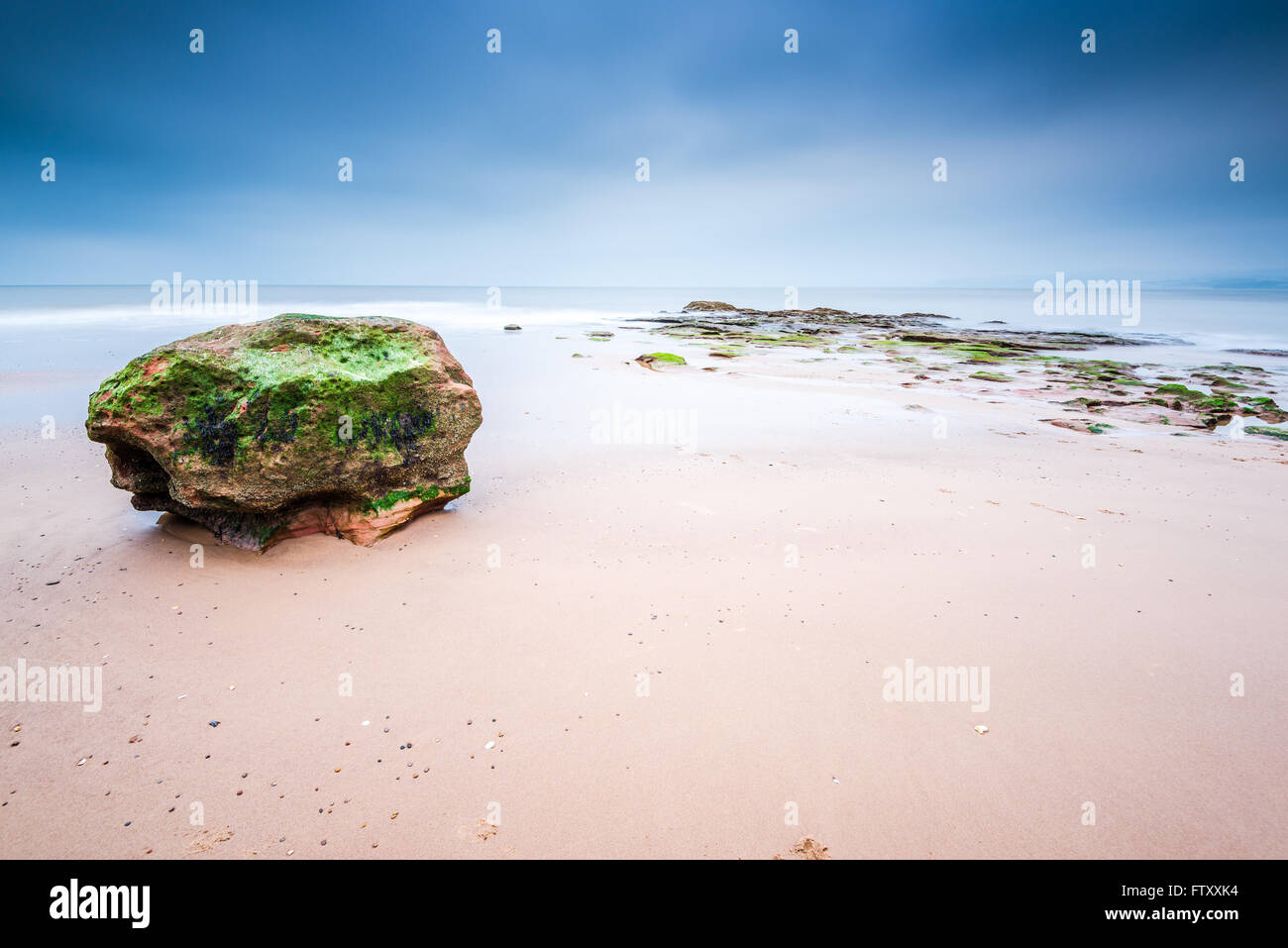 La formation de Red Rock Beach à Exmouth dans le Devon, Royaume-Uni. Une longue exposition blured l'eau de mer. Banque D'Images