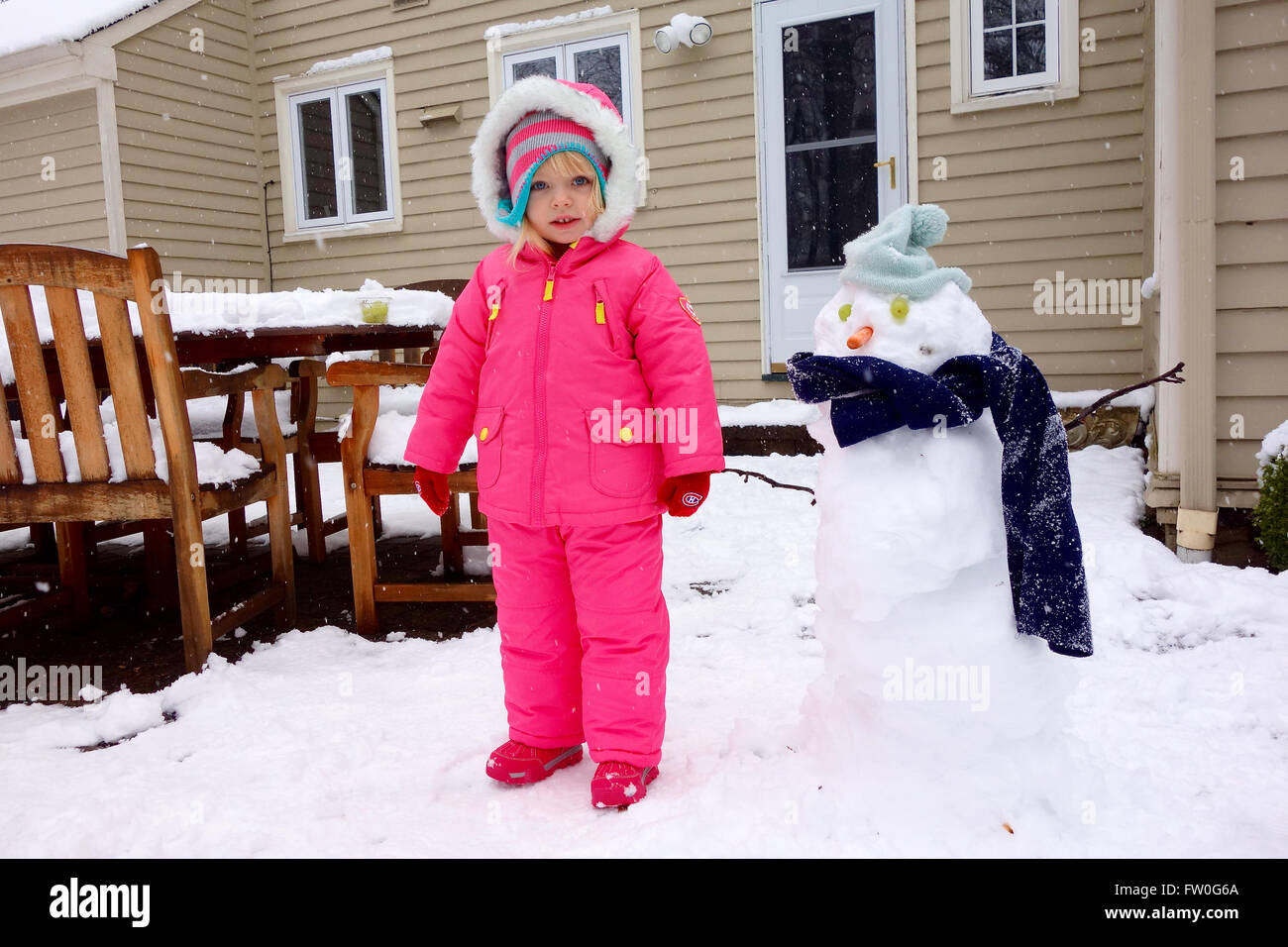 Jeune fille jouant dans la neige avec snowman Banque D'Images