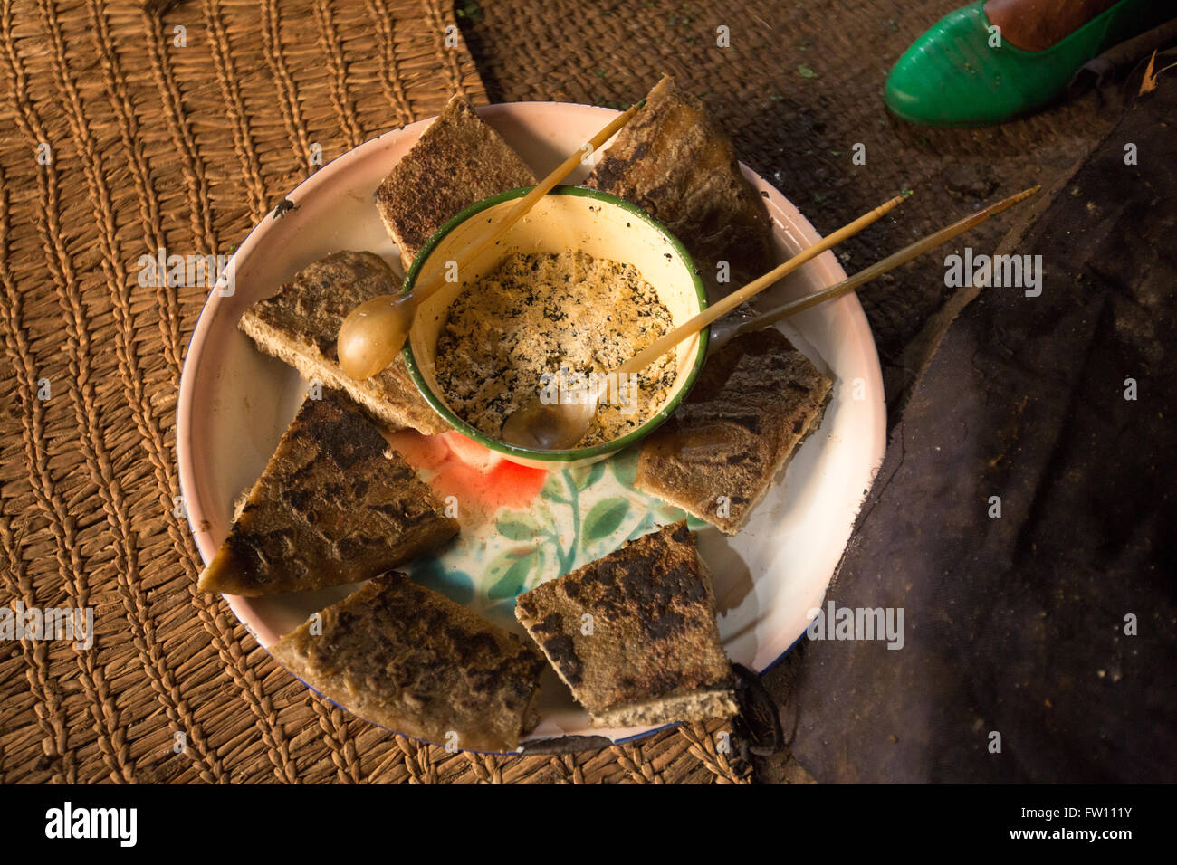 Gibi Gurage village, l'Éthiopie, octobre 2013 Maraganesh Waldemikel, 60 ans, se prépare avec du fromage et pain kocho vert légumes cuits. Banque D'Images