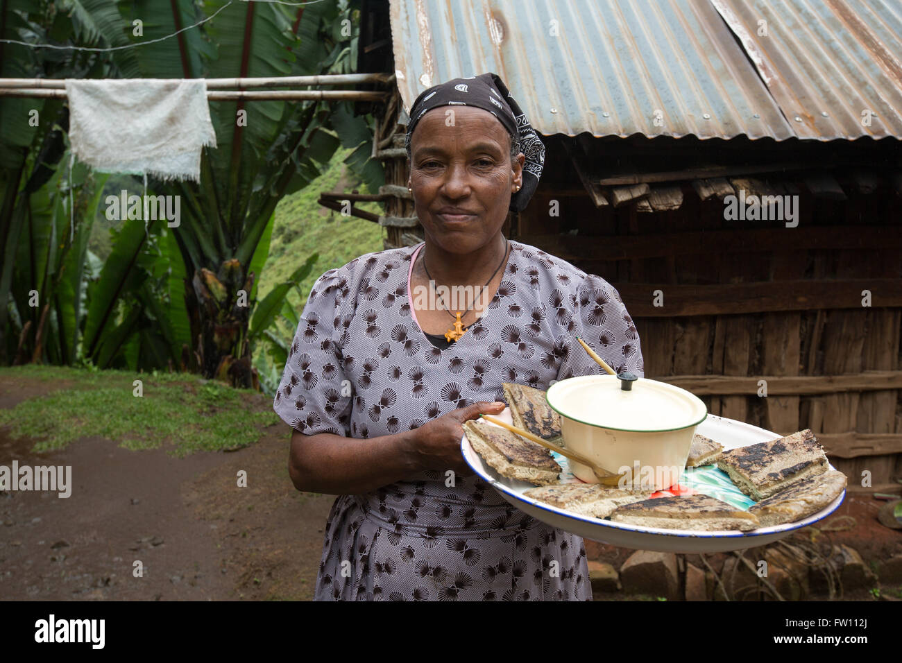 Gibi Gurage village, l'Éthiopie, octobre 2013 Maraganesh Waldemikel, 60 ans, se prépare avec du fromage et pain kocho vert légumes cuits. Banque D'Images