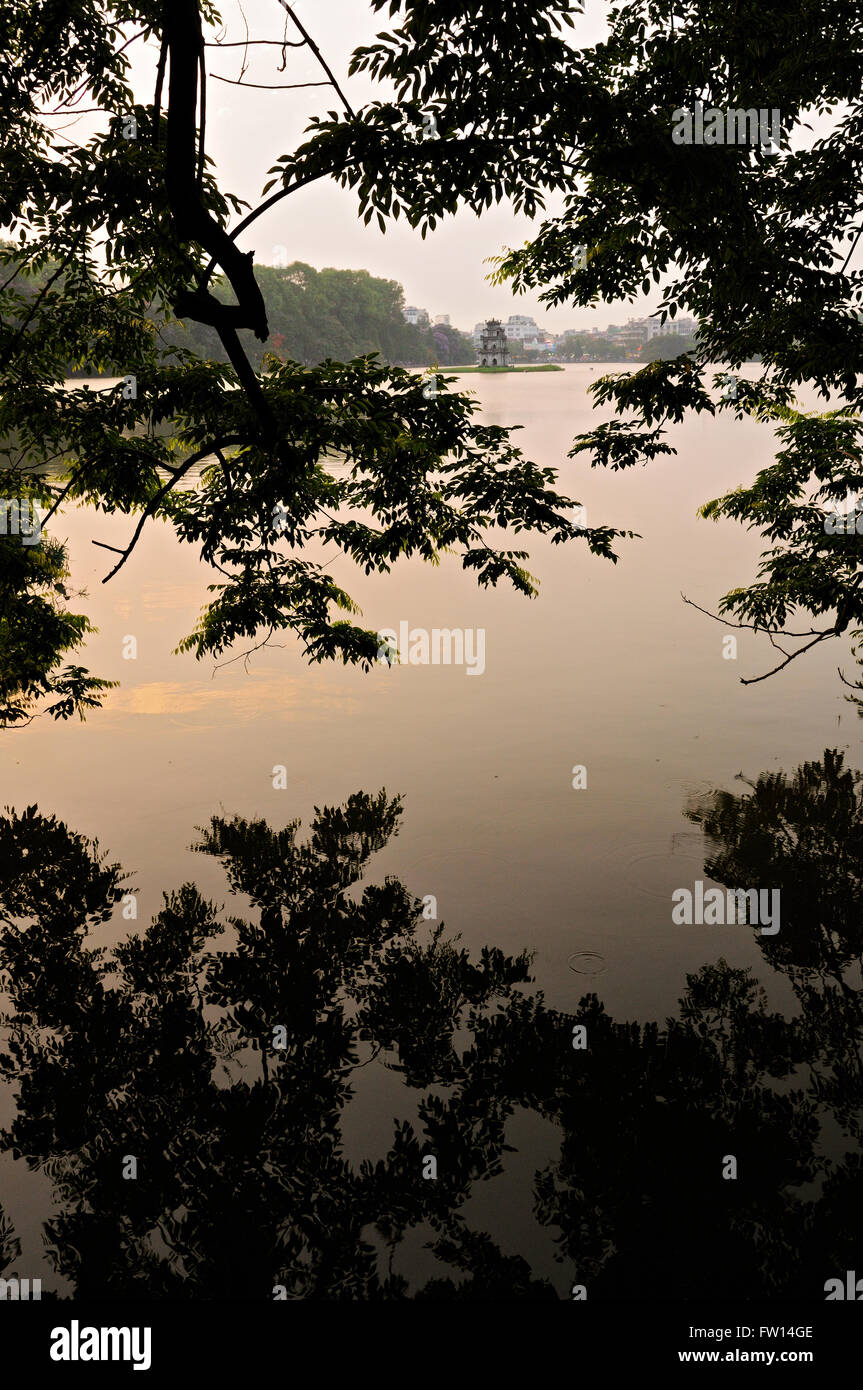 Reflet d'un arbre dans le lac Hoan Kiem au coucher du soleil avec la tour de la Tortue (Thap Rua) dans la distance, Hanoi, Vietnam Banque D'Images