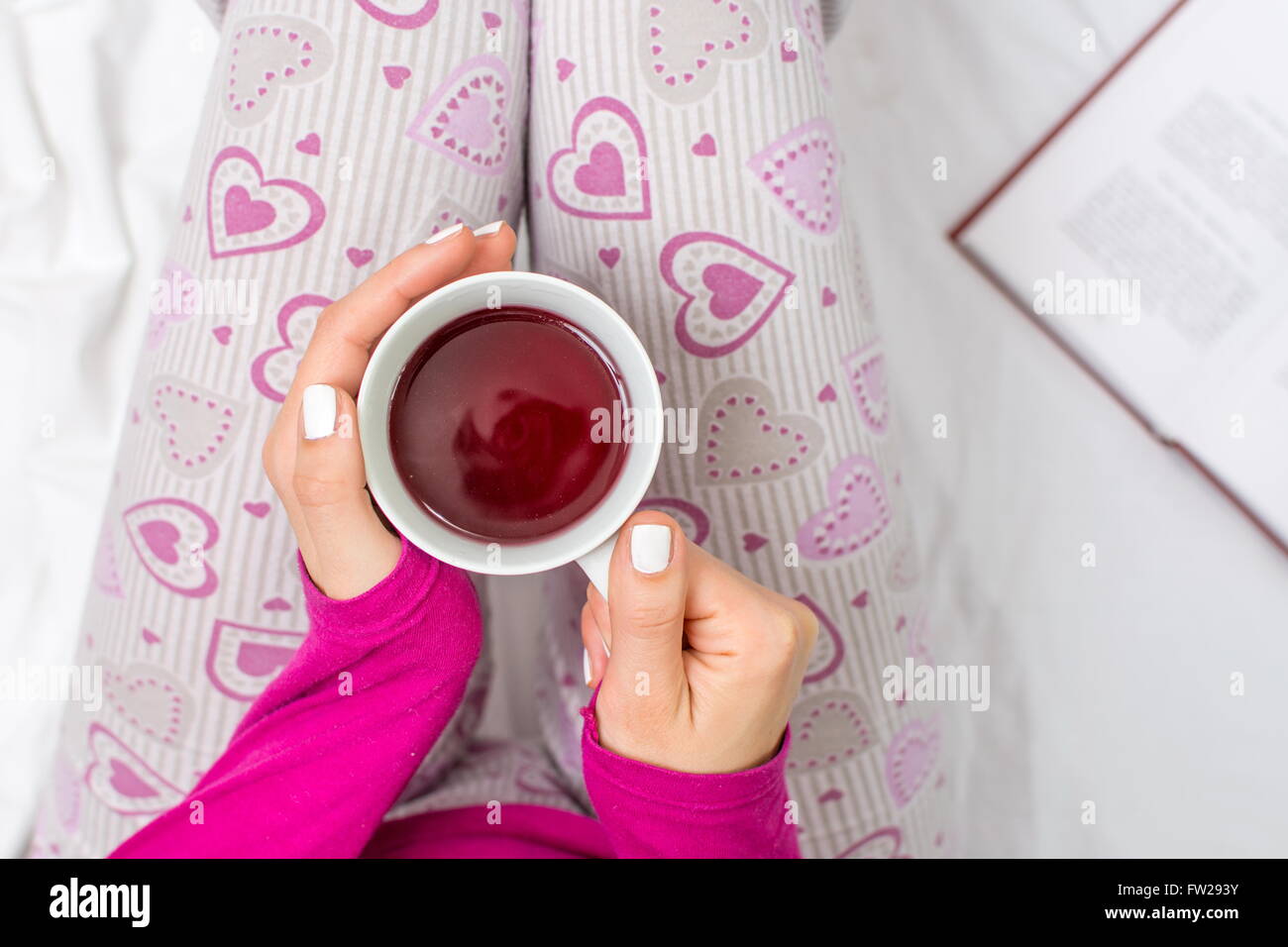 Femme ayant une tasse de thé au lit Banque D'Images