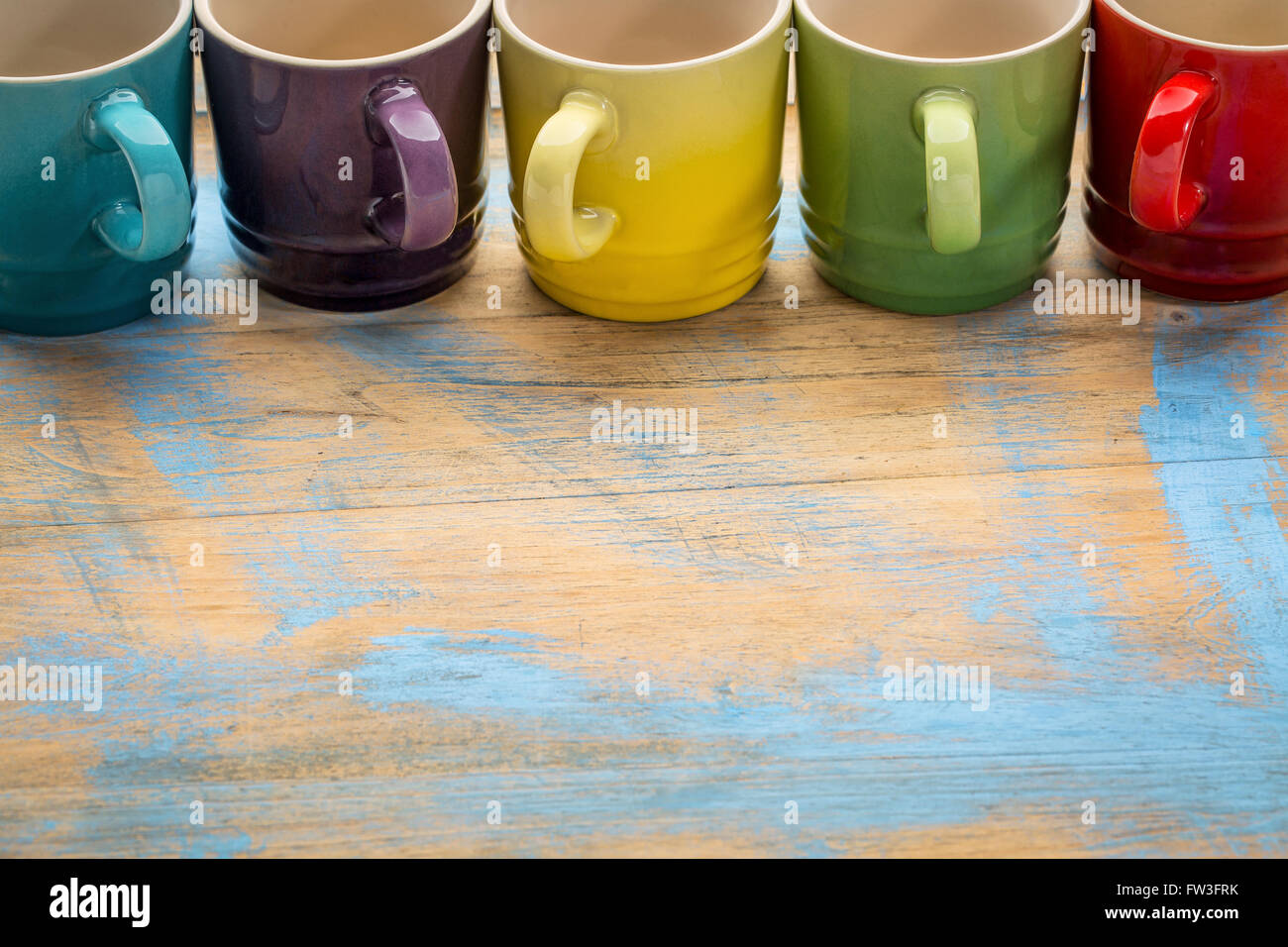 Une rangée de tasses à café en grès coloré vide contre grunge le bois peint avec une copy space Banque D'Images