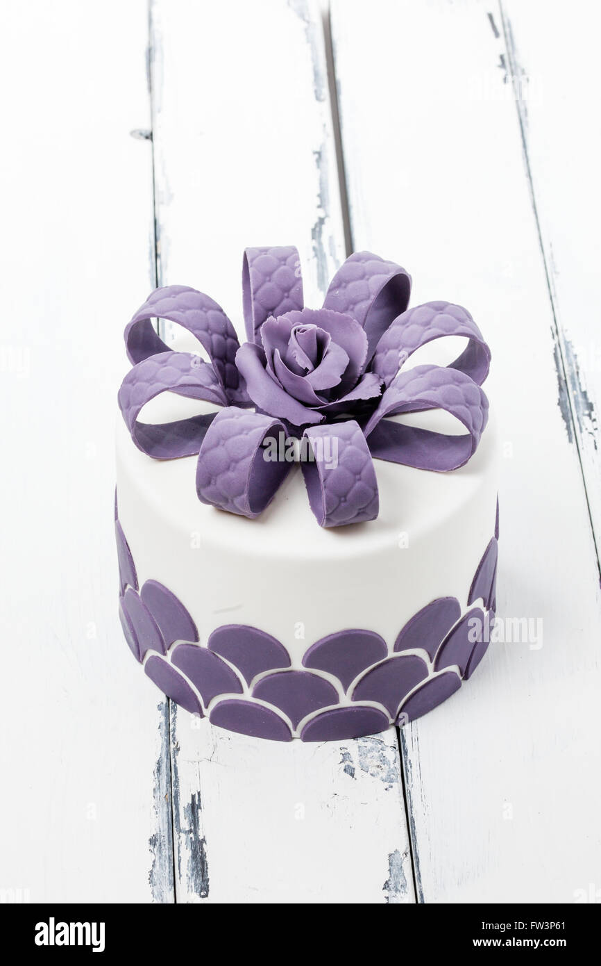 Joli gâteau décoré avec un noeud sur l'arrière-plan vintage lilas Banque D'Images