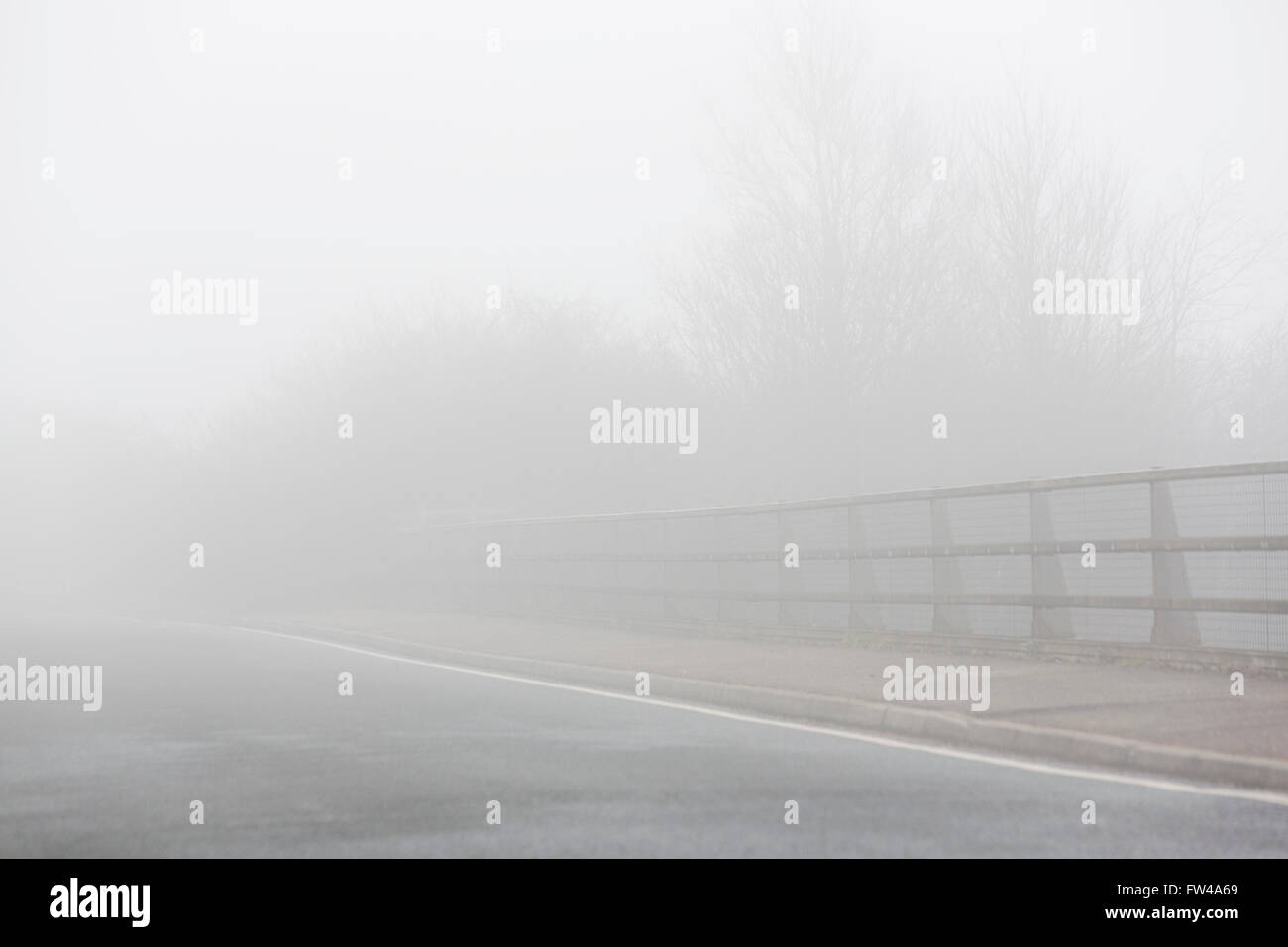 Un pont sur une route avec garde-corps disappeaaring dans la brume. Banque D'Images