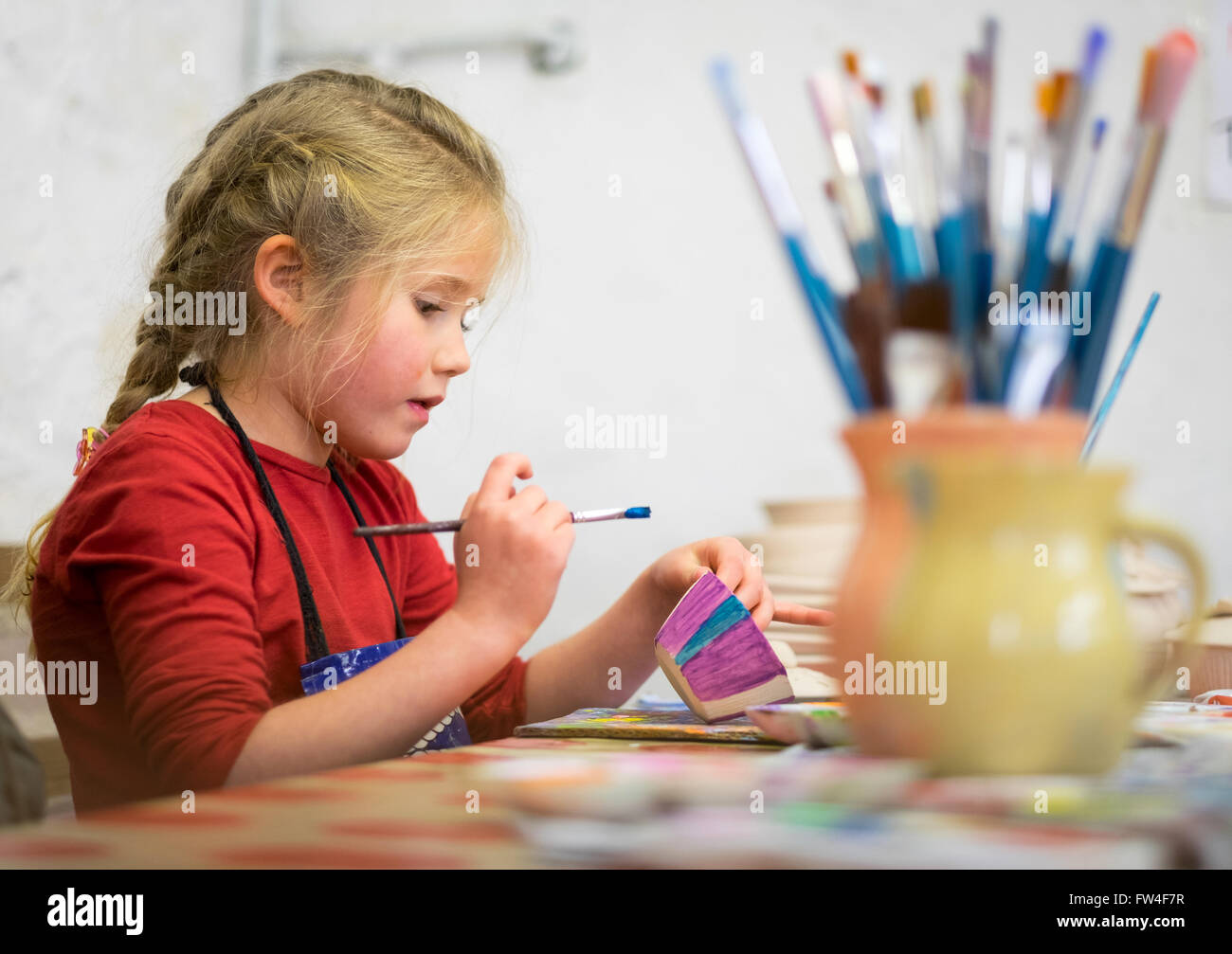 Une jeune fille part en peinture d'un pot dans un studio d'art Banque D'Images