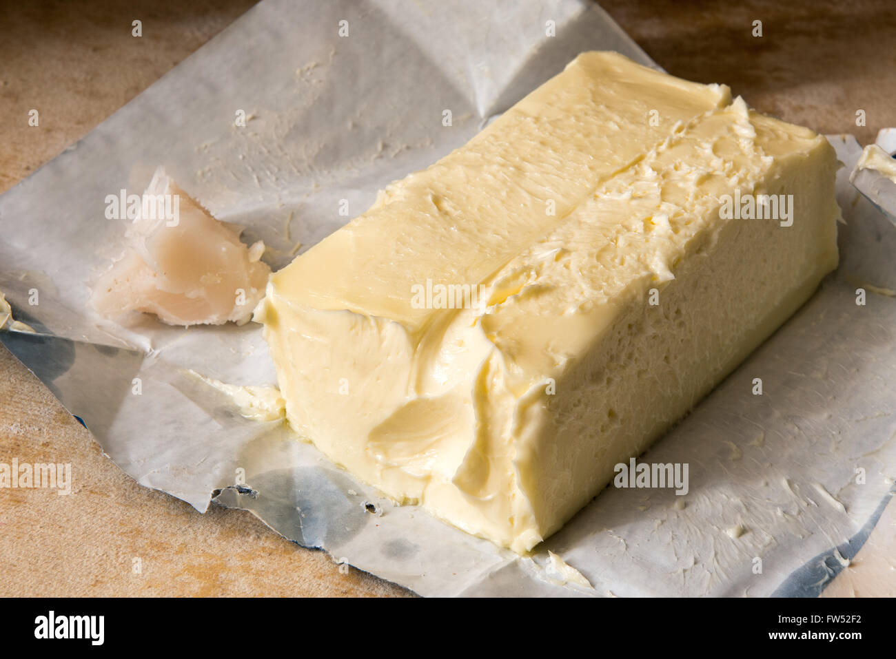 Close up sur un grand pat de beurre de ferme avec l'enveloppe ouverte sur une table en bois dans une boulangerie pour utilisation comme ingrédient de cuisson Banque D'Images