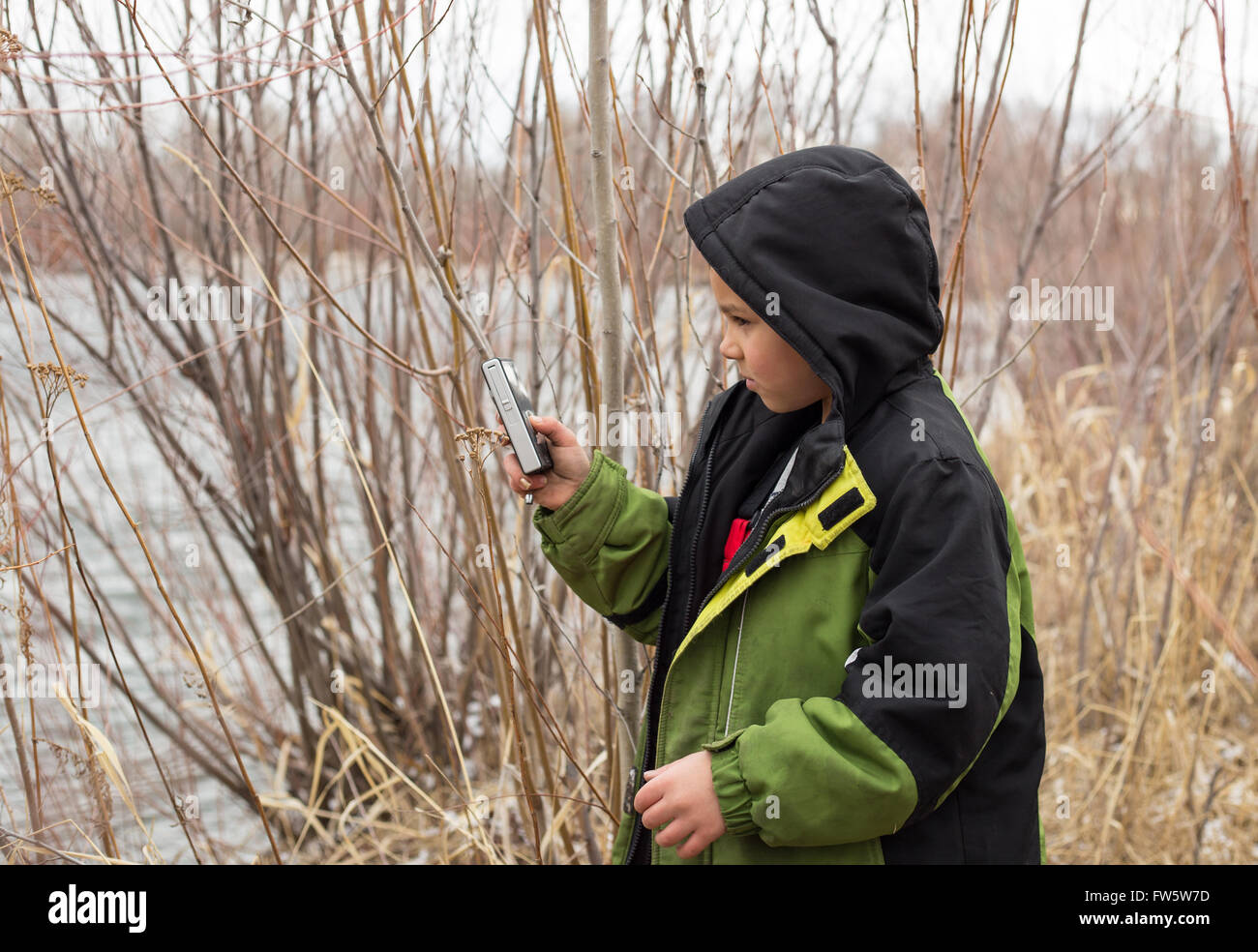 Enfant jouant sur dispositif mobile de prendre des vidéos à l'extérieur. Banque D'Images