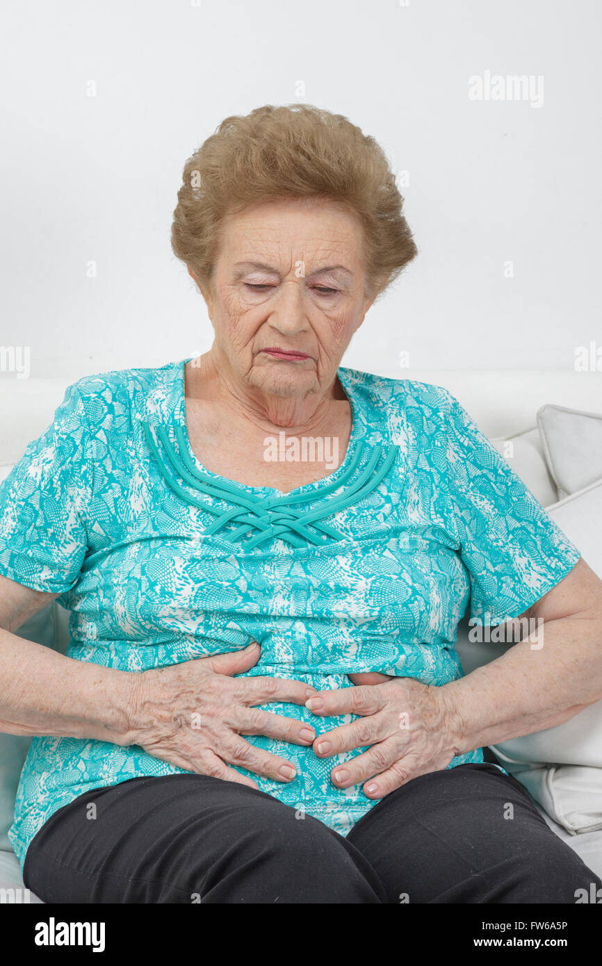 Une femme âgée détient son estomac à cause de la douleur. Banque D'Images