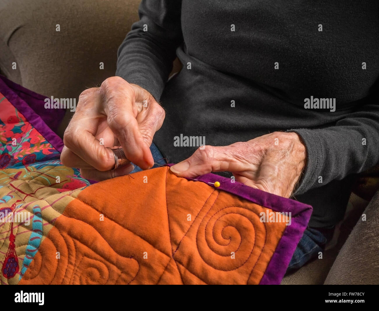 Photographie de la mains d'une femme de la haute couture la liaison sur un patchwork coloré. Banque D'Images