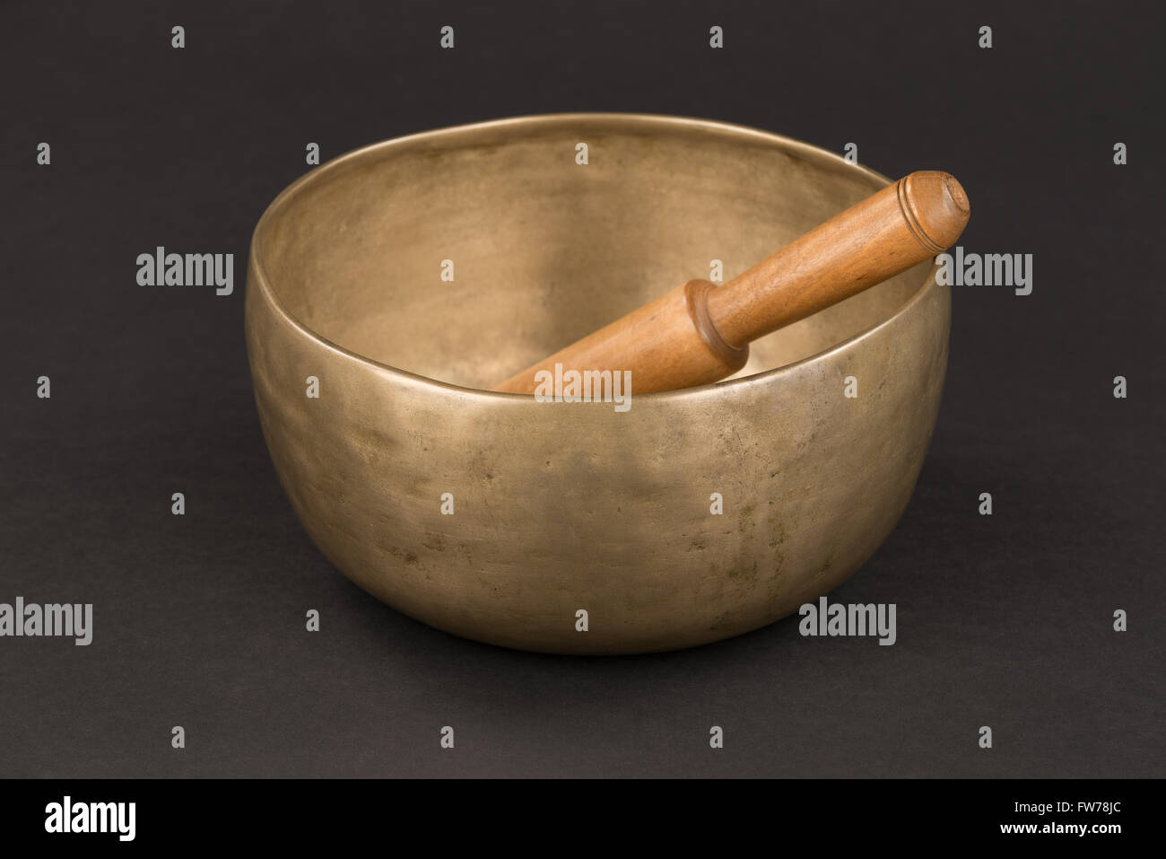 Simple, avec un bol chantant en bronze qui sonne en bois stick, sur fond noir Banque D'Images