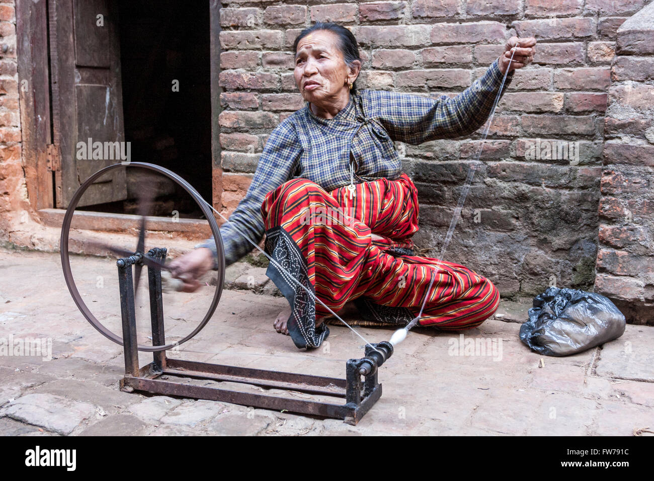 Bhaktapur, Népal. Woman Spinning Thread devant sa maison. Banque D'Images