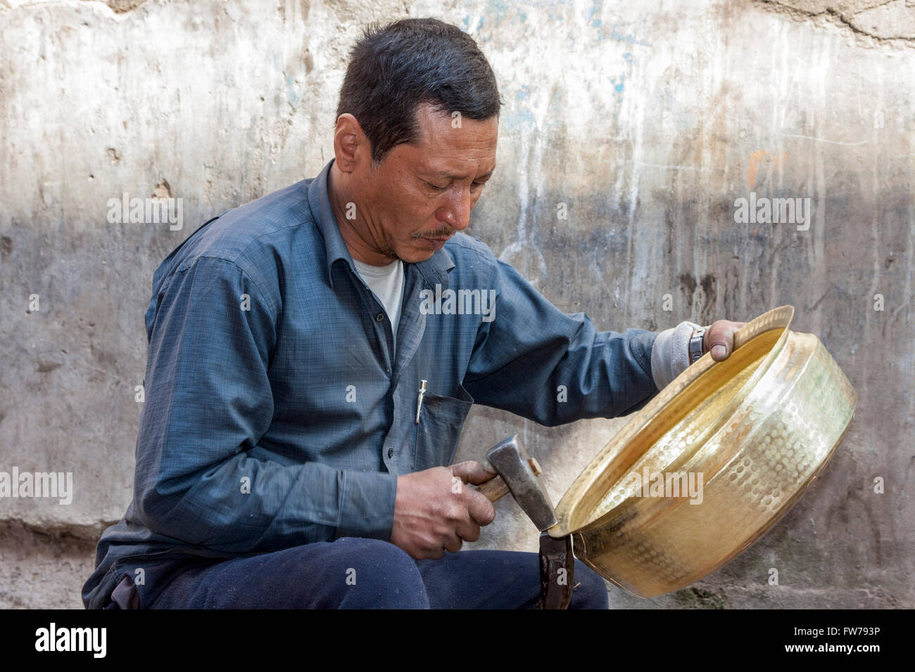 Bhaktapur, Népal. Métallier marteler un pot en forme. Banque D'Images