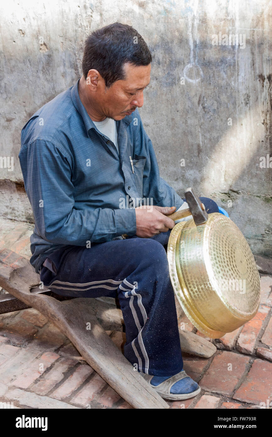 Bhaktapur, Népal. Métallier marteler un pot en forme. Banque D'Images