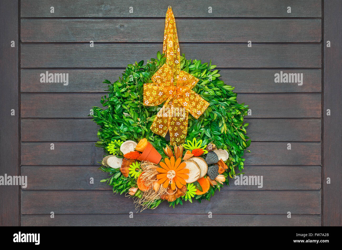 Couronne de printemps avec orange arc accroché sur la porte en bois foncé Banque D'Images