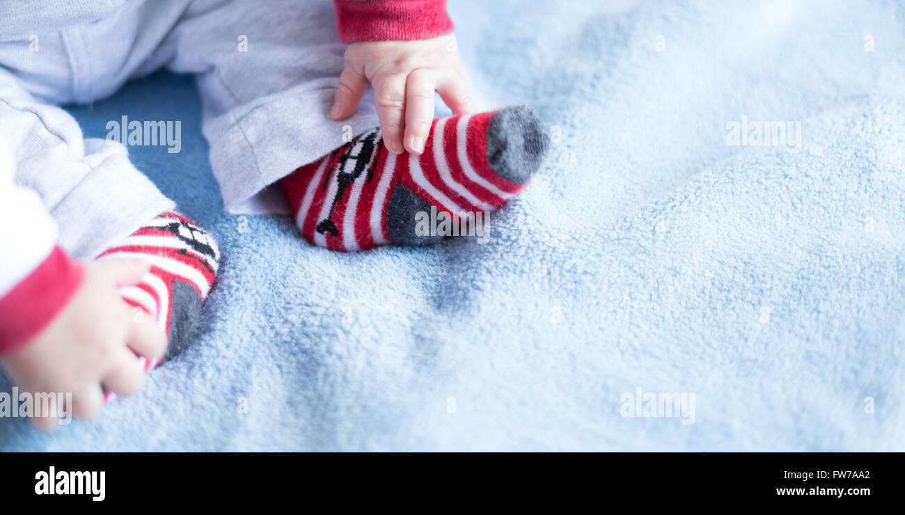 Nouveau-né avec chaussettes colorées, sur fond bleu Banque D'Images