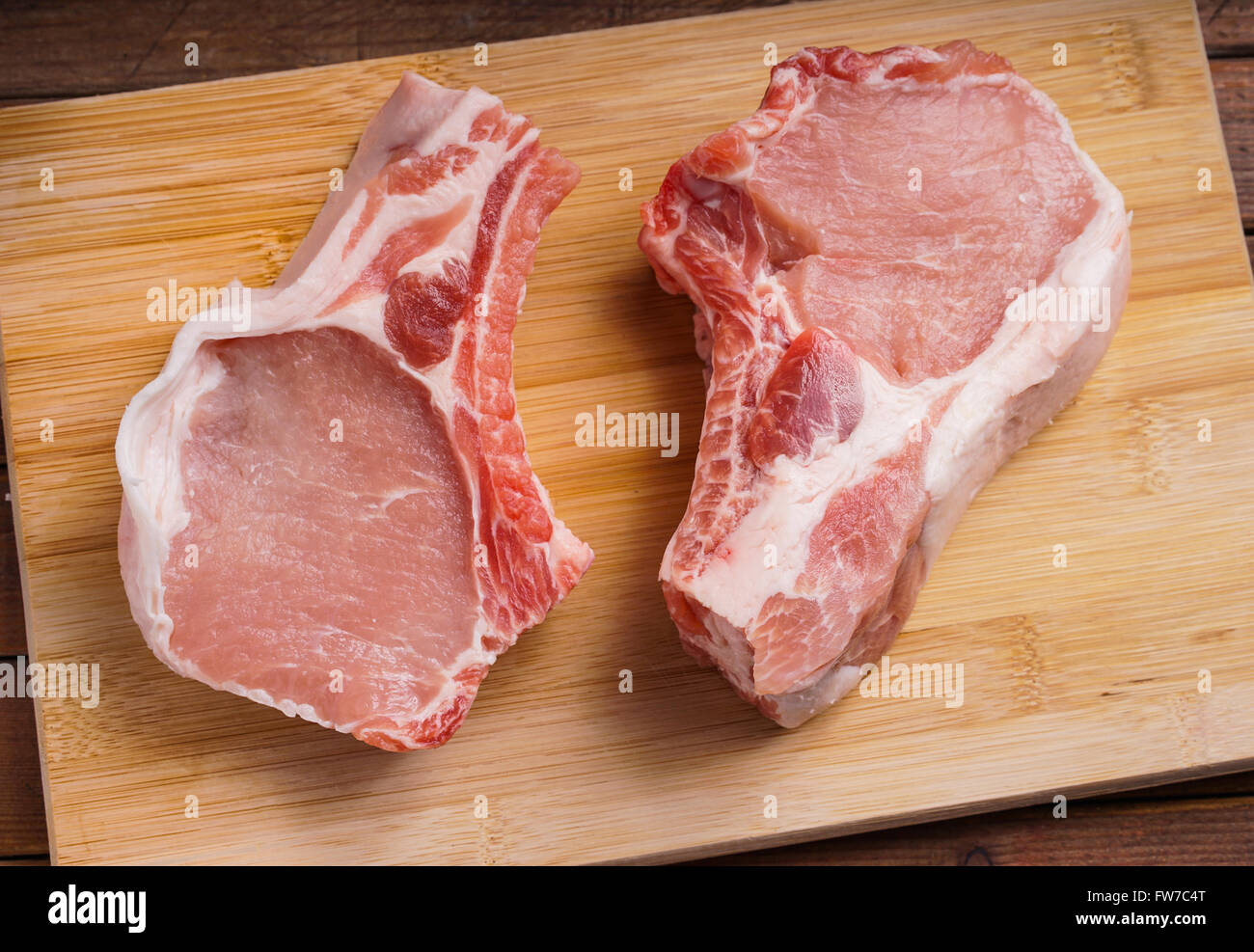 Côtelettes de porc cru, allongé sur une planche de bois pour la cuisson Banque D'Images