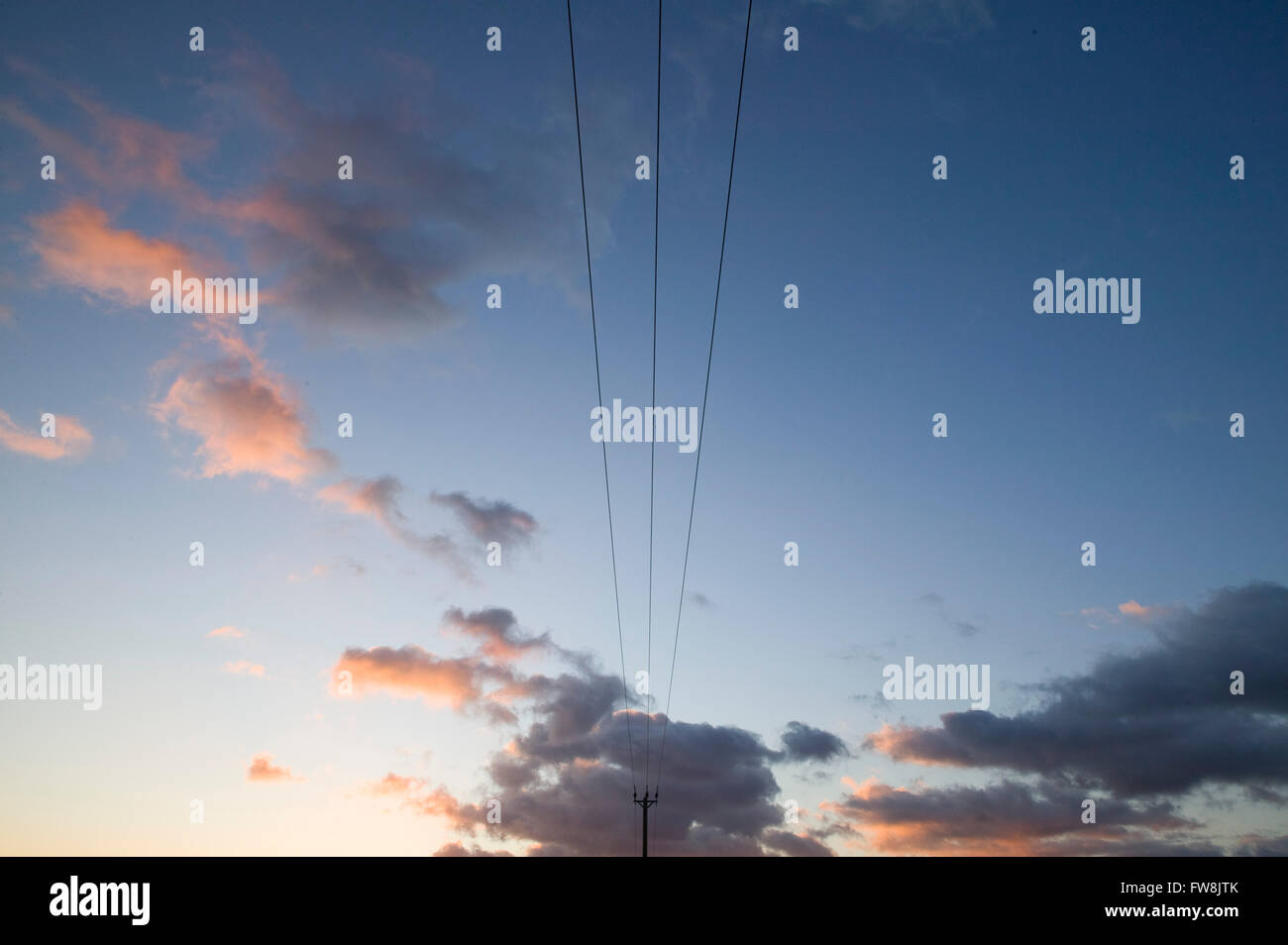 Les fils d'électricité criss cross la campagne grands poteaux sur l'alimentation pour les gens et les entreprises dans les zones basses de l'UK. Sur un hiver spectaculaire coucher du soleil l'image a un sentiment de paix et de sérénité tout en transmettant le lien entre l'alimentation, de la demande et l'effet sur notre environnement. Banque D'Images