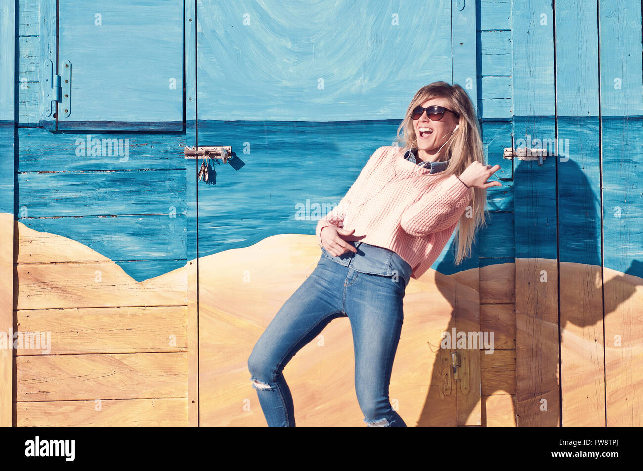 Jeune femme d'écouter de la musique avec des écouteurs et en imitant la guitare Banque D'Images