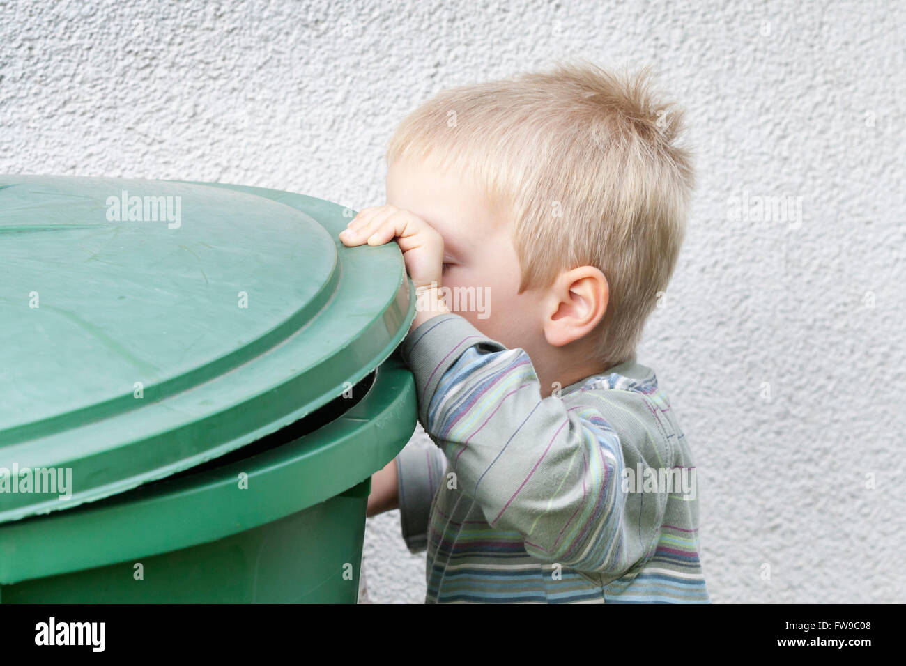Petit garçon regardant dans une poubelle Banque D'Images