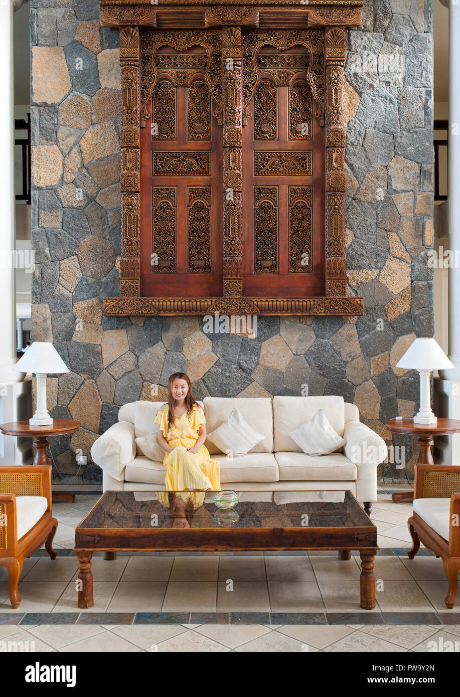 Femme assise sur un canapé dans le hall de l'hôtel Residence à l'Ile Maurice. Banque D'Images