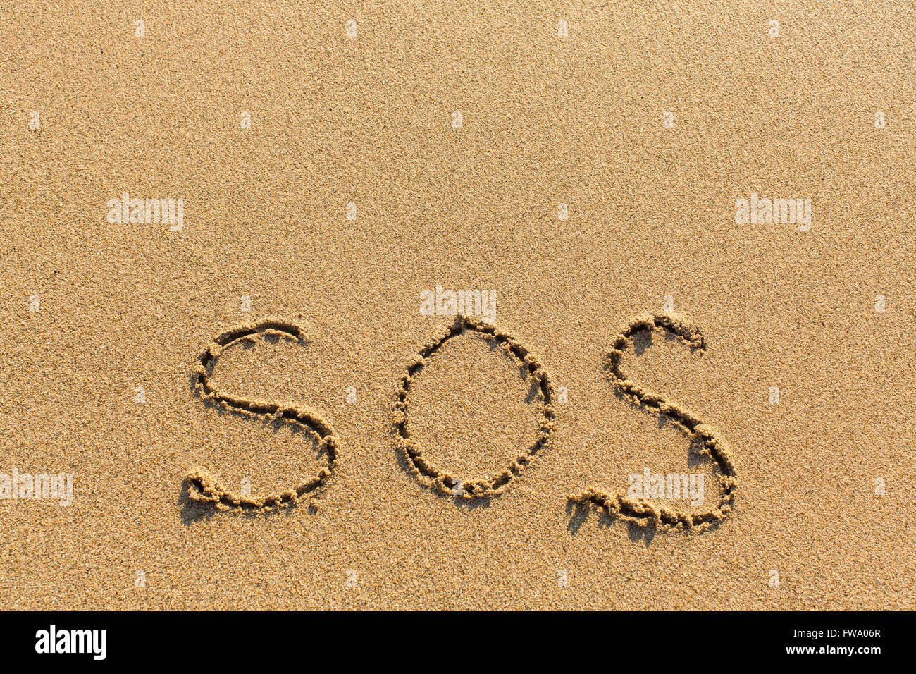 SOS - écrites manuellement sur la texture du sable de la mer. Banque D'Images