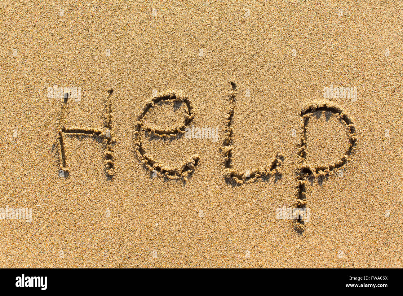 Aide - written manuellement sur la texture du sable de la mer. Banque D'Images