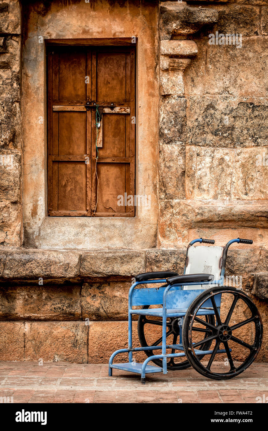 Fauteuil roulant sur un arrière-plan d'un mur de pierre Banque D'Images