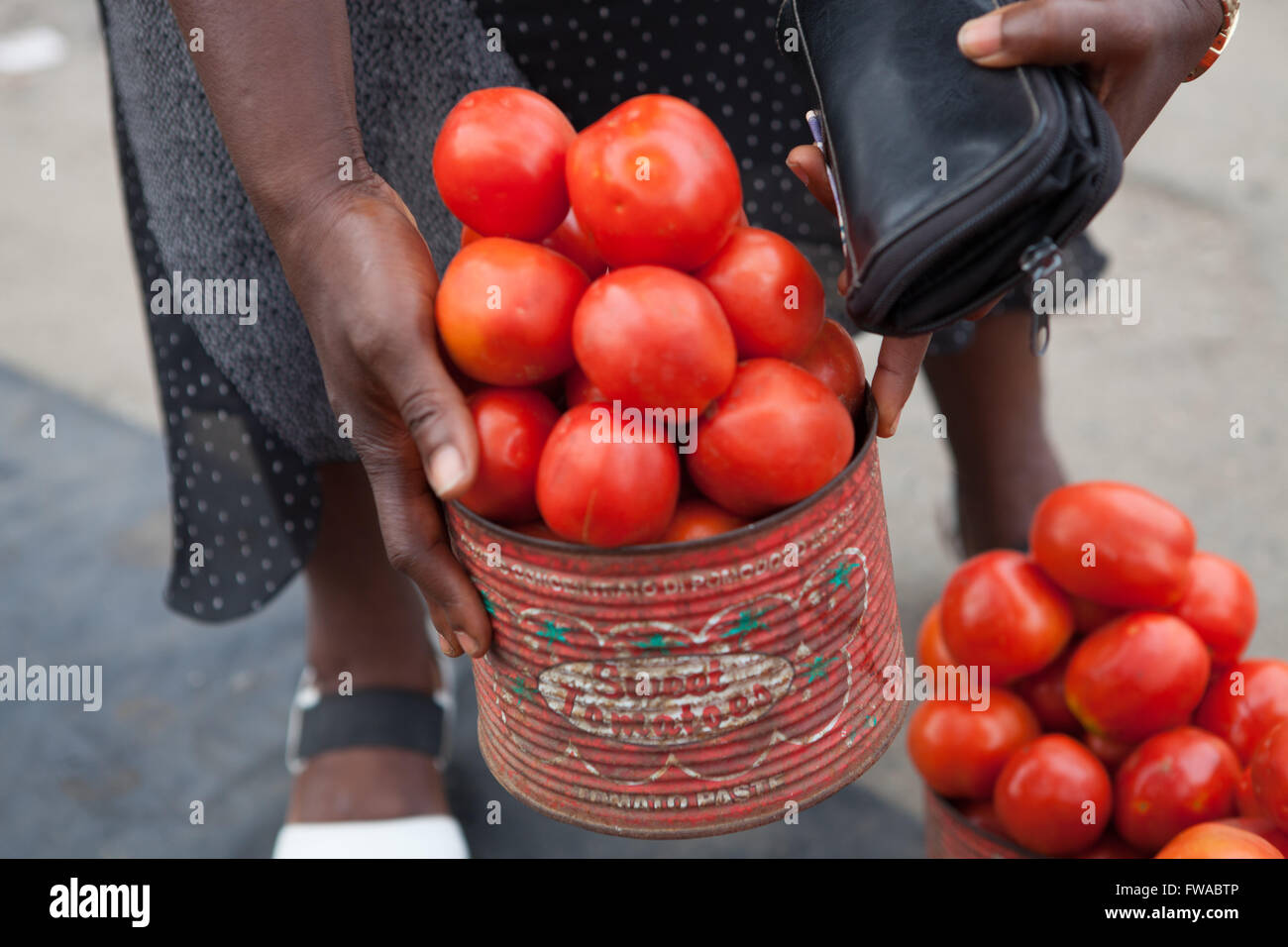 Une femme d'acheter une boîte de tomates fraîches, d'un marché de rue, le Nigeria, l'Afrique Banque D'Images