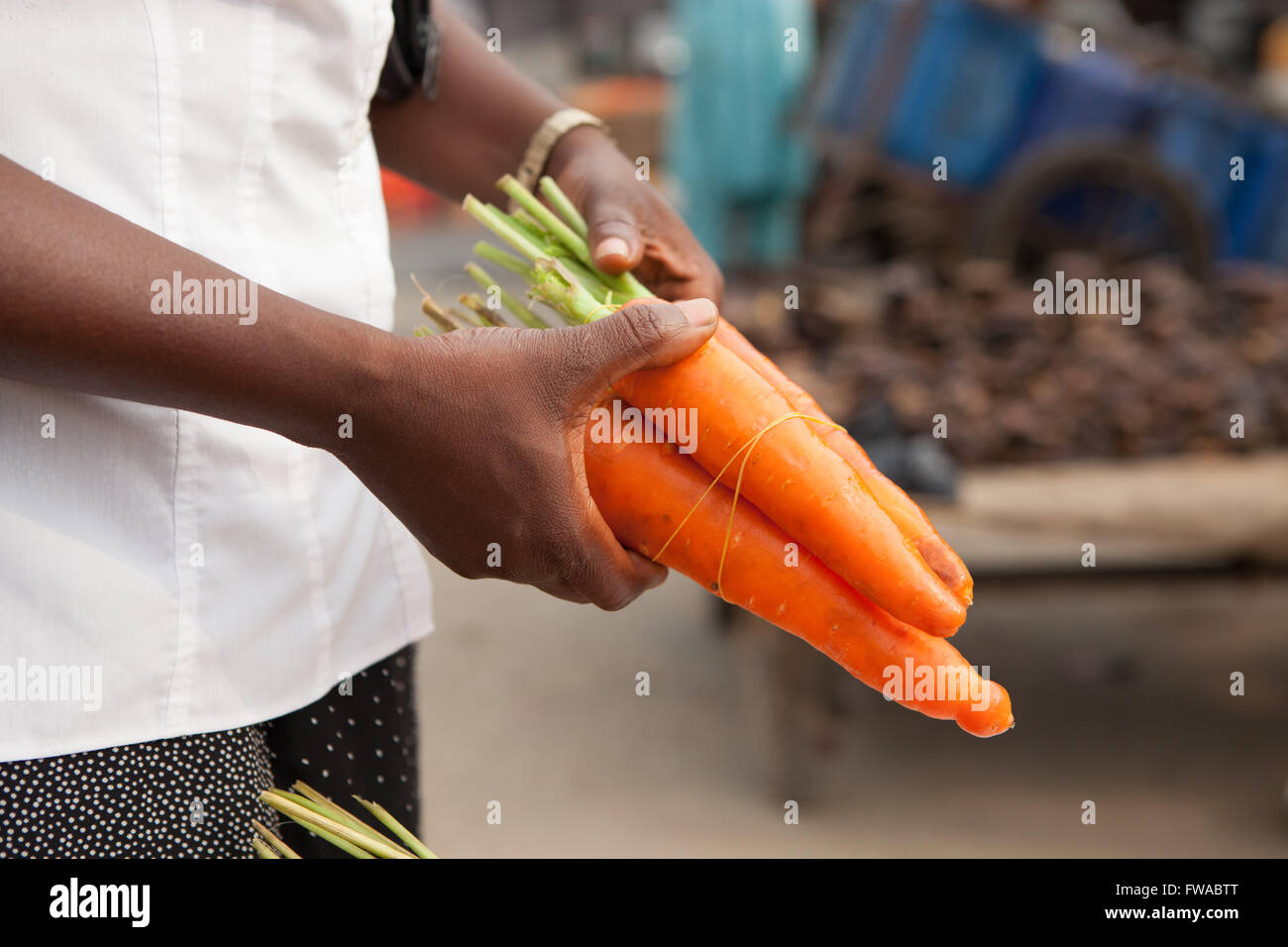 Une femme d'acheter un tas de carottes d'un marché de rue le Nigeria, l'Afrique Banque D'Images