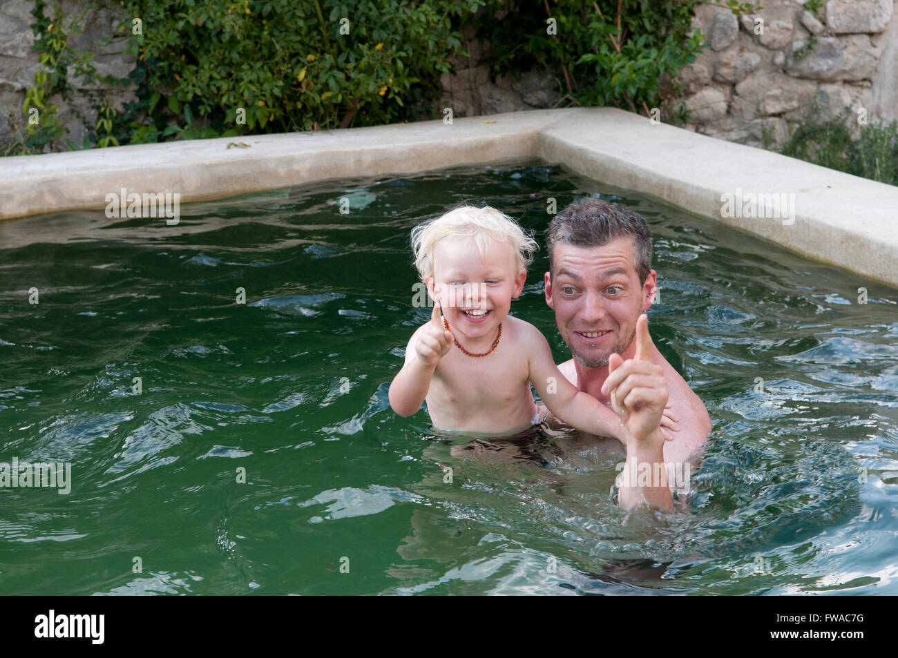 Père et fils en vacances à jouer dans une piscine Banque D'Images