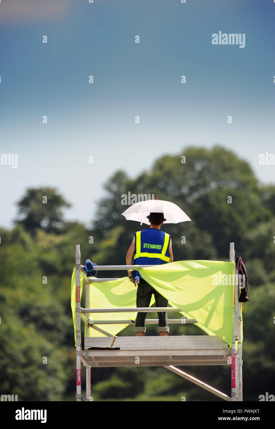 Un steward obtient par avec un minimum d'ombre pendant un an par temps chaud au festival de Glastonbury 2010, UK Somerset Pilton Banque D'Images