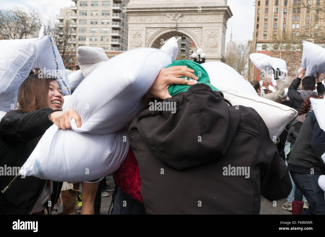 Jeune femme homme frapper avec un oreiller pendant la plus grande guerre d'oreillers à Washington Square Park, New York. Banque D'Images