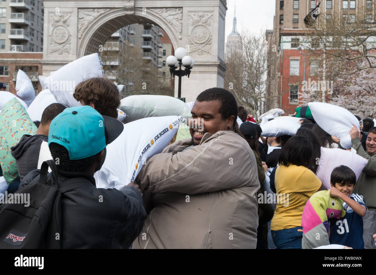 Jeune homme afro-américains d'avoir du plaisir avec son ami dans le plus grand pillow fight, Washington Square Park, New York. Banque D'Images