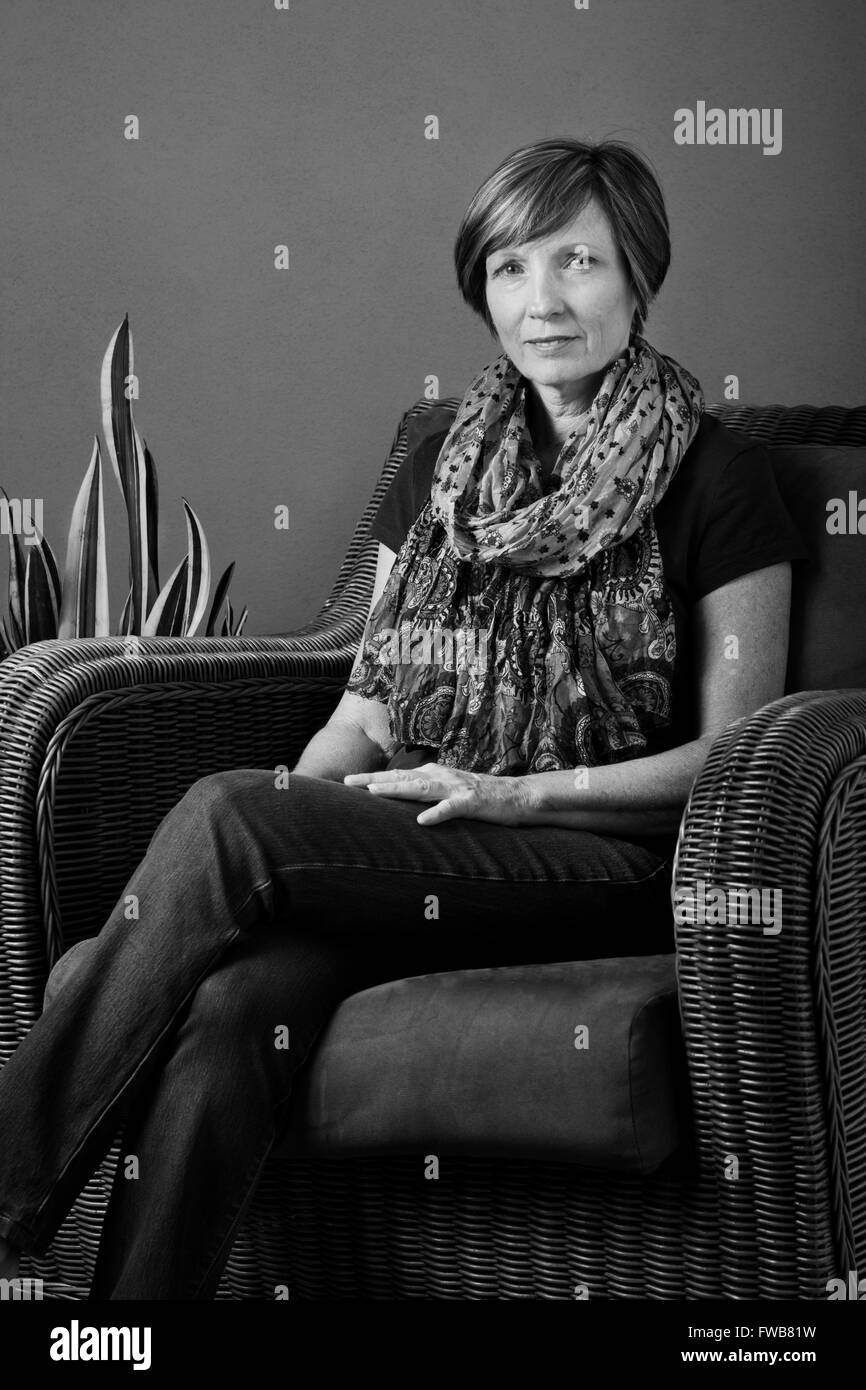 Portrait of middle-aged woman sitting in chair en noir et blanc Banque D'Images