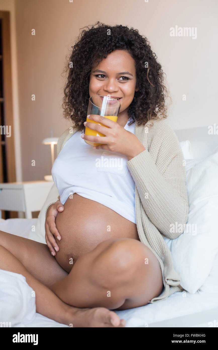 Pregnant woman drinking orange juice dans la chambre Banque D'Images