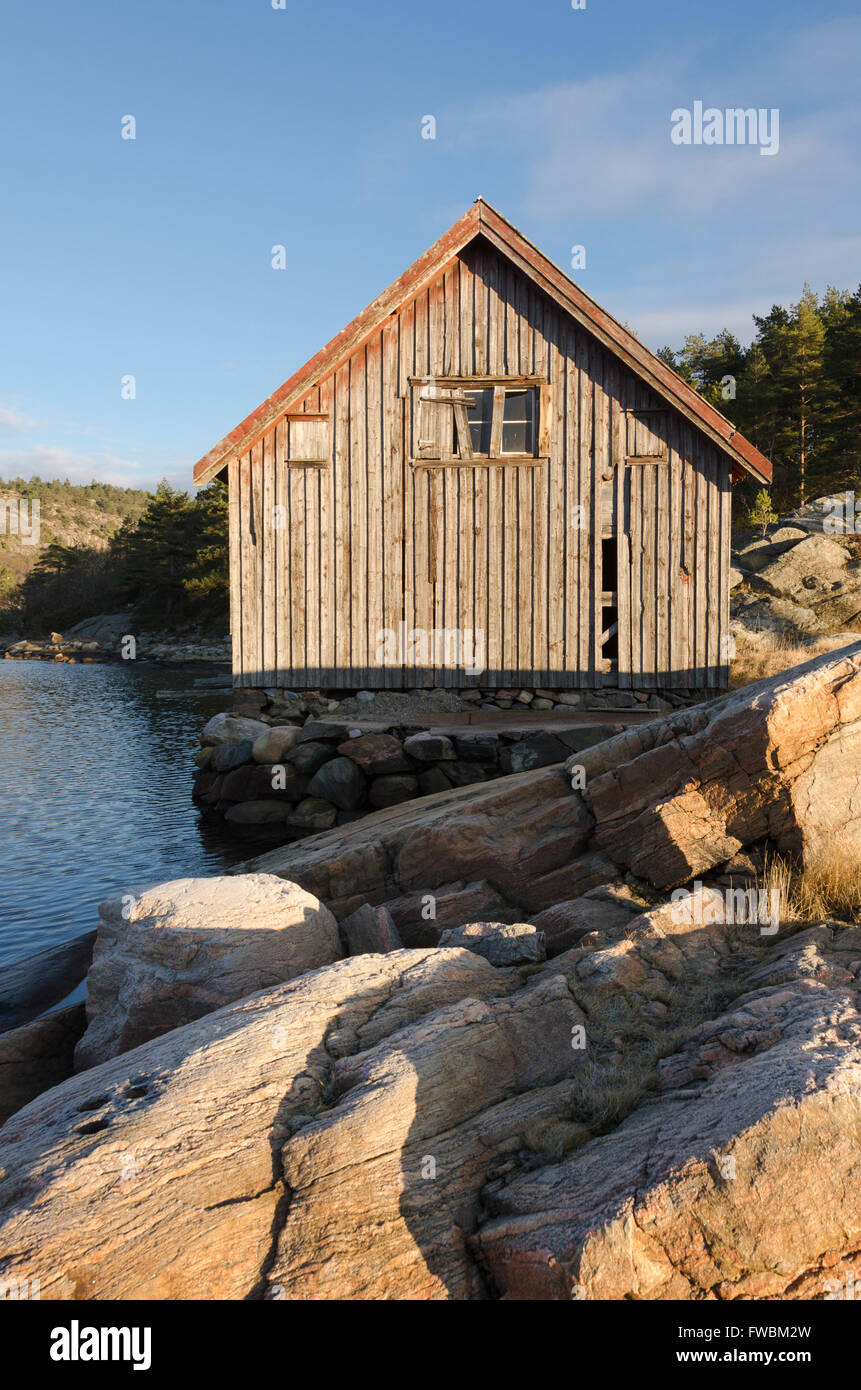 Ancien hangar à bateaux sur l'eau debout entre la pierre et le soleil Banque D'Images