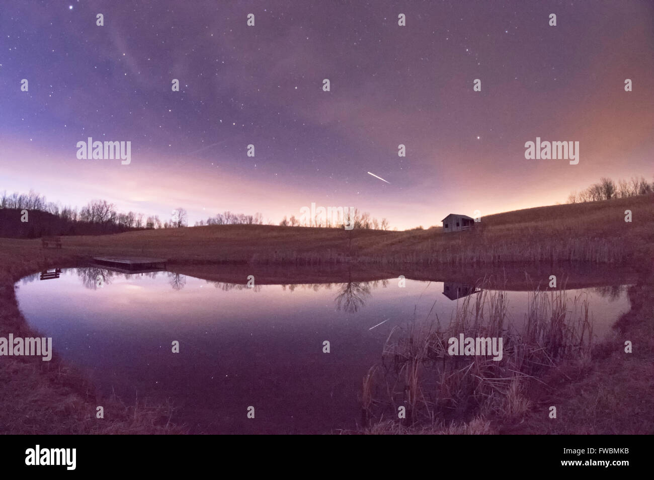La station spatiale internationale rayures verticales sur le ciel nocturne juste après le crépuscule réfléchi sur l'étang. Banque D'Images