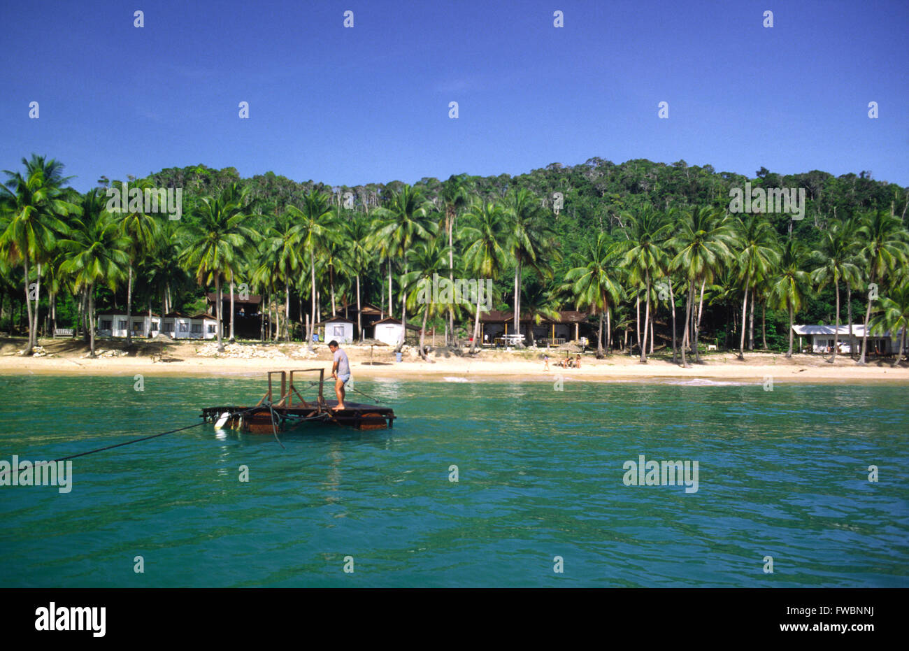 Sibu island au large de la Malaisie et les décideurs ont besoin de vacances à bord d'un petit radeau à partir de leur bateau et sont ensuite tiré sur le radeau par corde à travers l'île. L'île a un style chalet / hut resort et est typique des petites îles de la région offrant calme solitaire se casse sur la magnifique bordée de palmiers des plages de sable. Banque D'Images