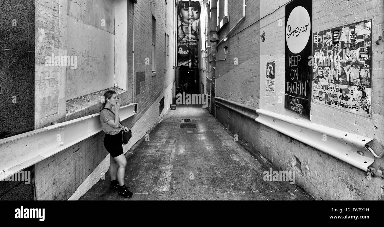 Girl taking pause cigarette en alley en dehors du lieu de travail. Le noir et blanc avec des graffitis sur les murs Banque D'Images